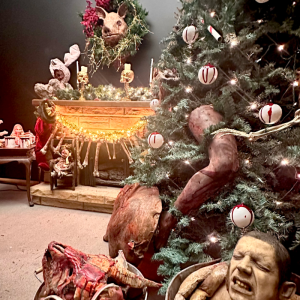 Creepy Christmas scene with a decorated tree, pig head wreath, and horror-themed ornaments.