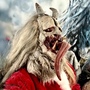 Person in a scary Krampus costume with horns and long tongue.