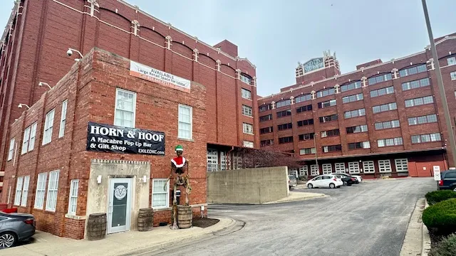 Brick buildings with 'Horn & Hoof' bar sign and statue on street corner.