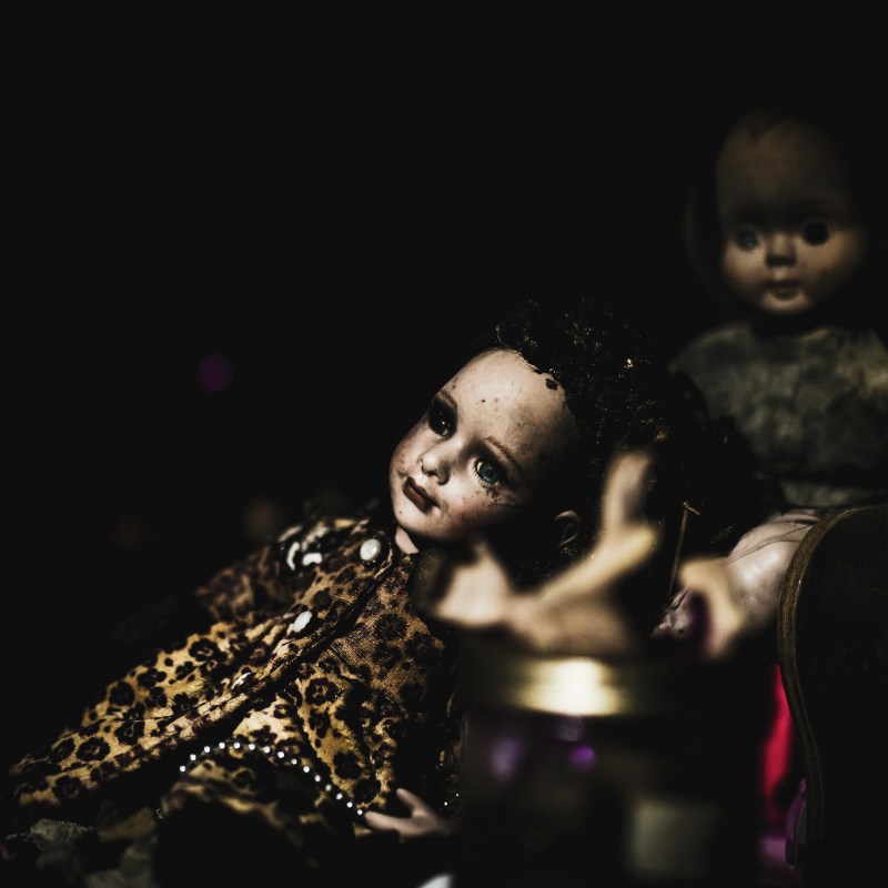Two vintage dolls in dim lighting with one wearing leopard print clothing.