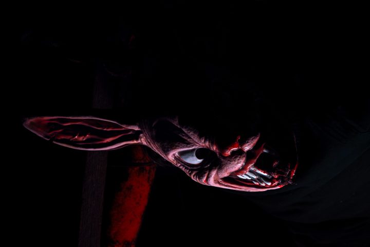 Creepy figure in a dark scene with an animal-like mask, part of the 'Exiled Trail of Terrors' event.