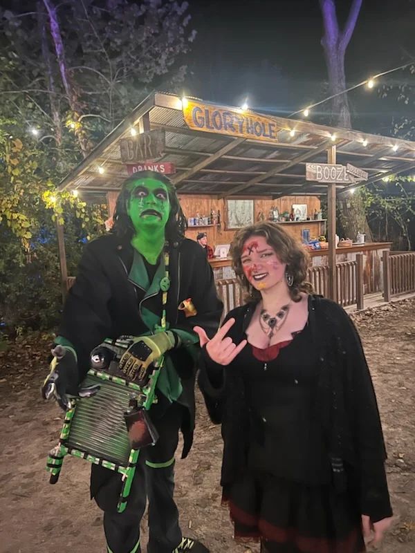 Two characters outside a rustic Carnival bar under string lights