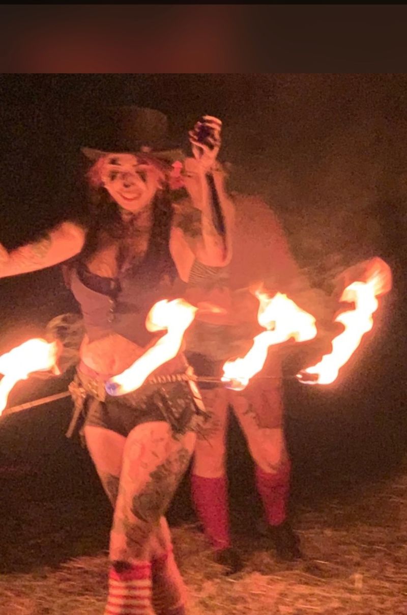 A costumed performer with a burning multi-wick hoop during a fire act