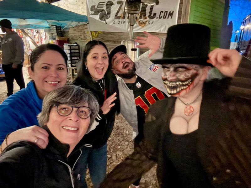 Friends pose with a top-hatted Carnival character