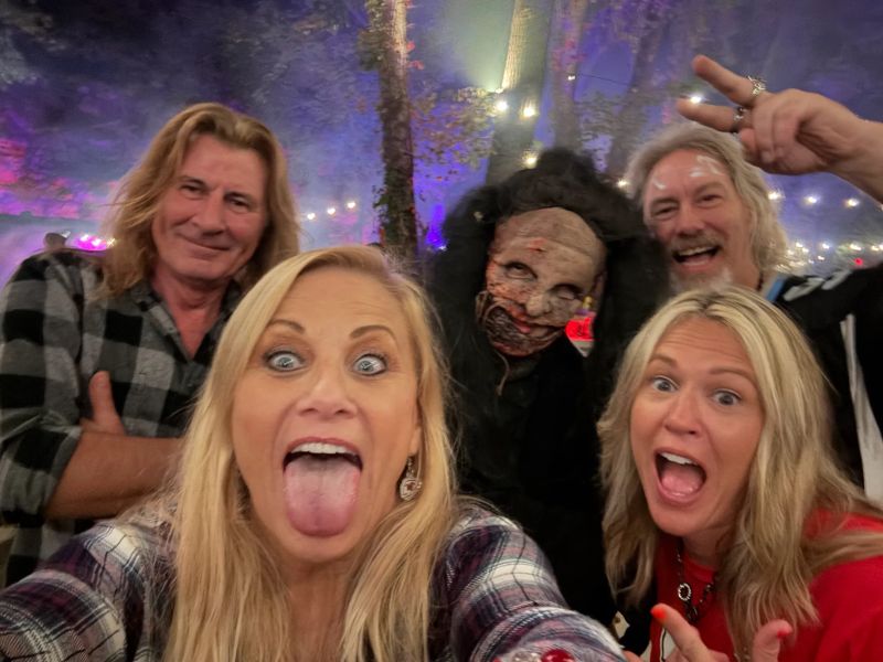 A group of guests takes a selfie with a masked character beneath the Carnival lights
