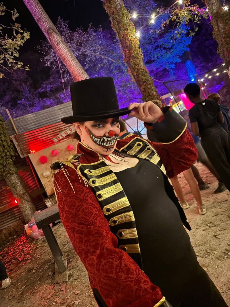 A grinning top-hatted Carnival character tips their hat
