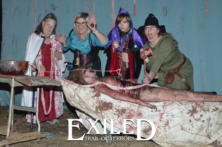 Guests in costume posing at an Exiled haunted operating-room set