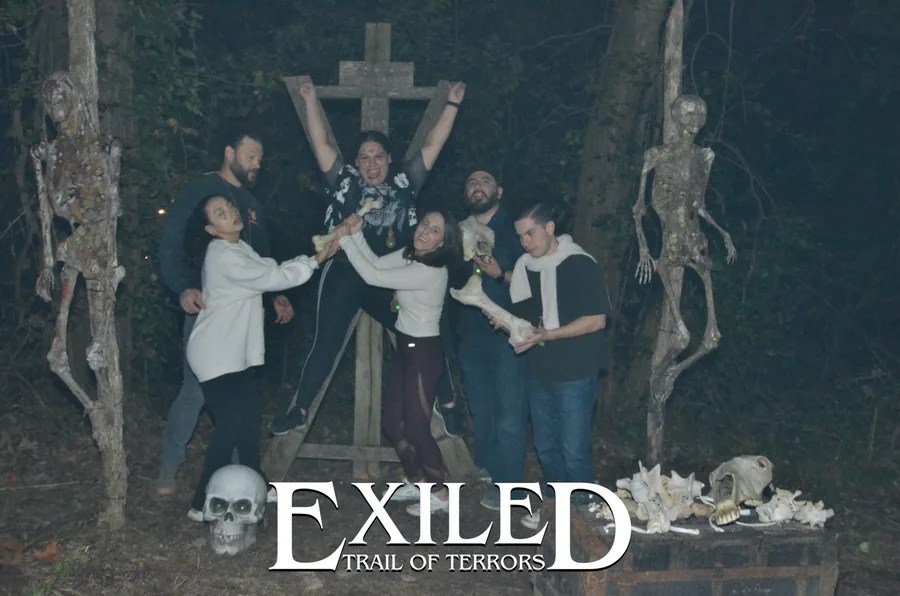 A group of guests posing between skeletons on the Trail of Terrors