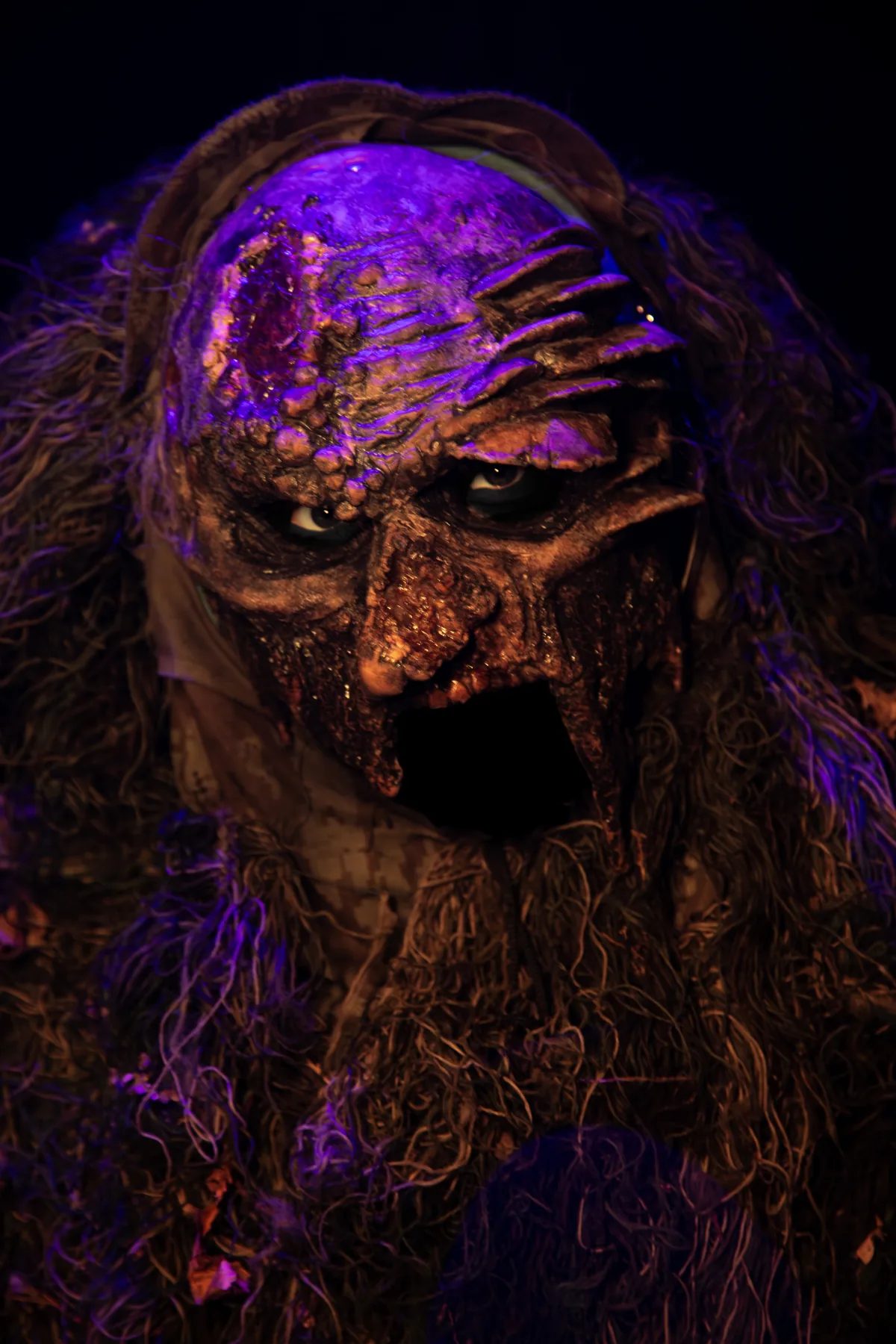 An Exiled creature with glowing amber eyes and a snarling mask